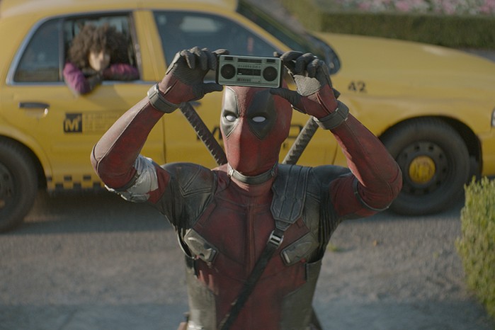Ryan Renyolds as Wade Wilson/Deadpool and Zazie Beetz as Domino in Deadpool 2 with Deadpool holding a speaker above his head