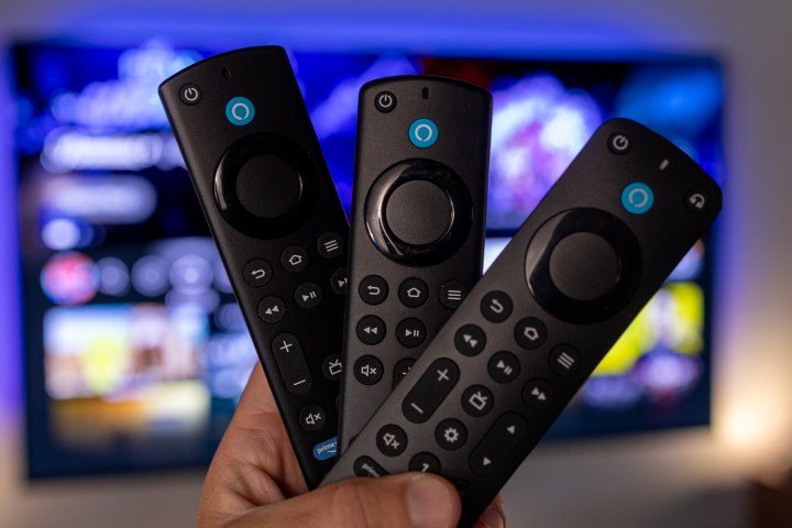 Bir televizyonun önünde tutulan üçlü Amazon Fire TV uzaktan kumandası.