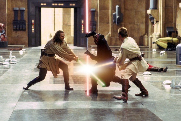 Three characters engaged in an intense lightsaber battle in a large room, two Jedi – Qui-Gon Jinn and Obi-Wan Kenobi – with green and blue lightsabers against a shadowy figure, Darth Maul, wielding a red lightsaber double blade.