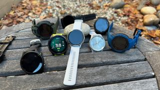 A pile of Garmin watches on a table: The Venu 3, Forerunner 965, 955, 265 and 255 Music, Instinct 2 Solar and 2X Solar, and Vivomove Trend.