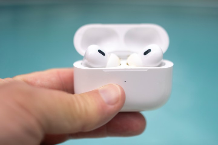 Arka planda yüzme havuzu bulunan açık bir kutuda bir çift Apple AirPods Pro.