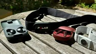 The Polar H10 and COROS heart rate monitor placed on a table next to two heart rate headphones, the Sennheiser Momentum Sport and the Anker Soundcore Liberty 4.