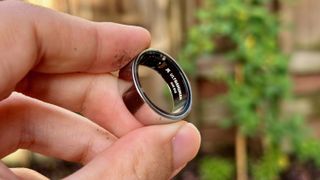 The Ultrahuman Ring Air held on the fingertips to show the Ultrahuman logo engraved inside.